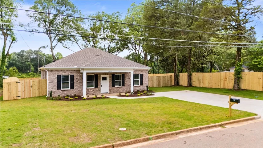 A newly constructed brick home featuring a fresh green lawn and a full privacy fence.