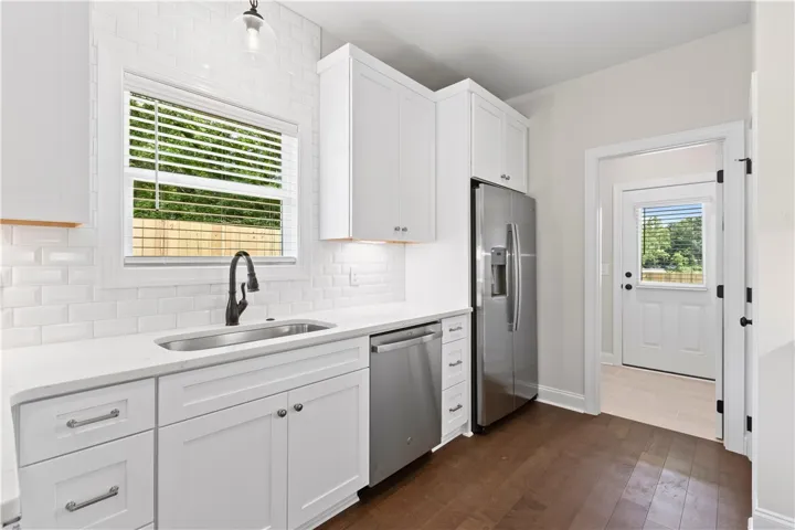 A well-lit kitchen features modern appliances and rich hardwood flooring.