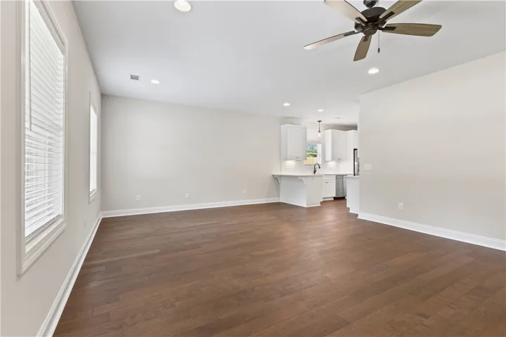 Hardwood flooring extends throughout this generous living space, seamlessly connecting to a modern kitchen.