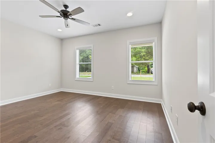 Hardwood floors and bright windows illuminate this spacious bedroom.