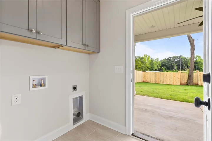Functional laundry space with custom overhead cabinetry and direct access to back porch with a private fenced backyard.