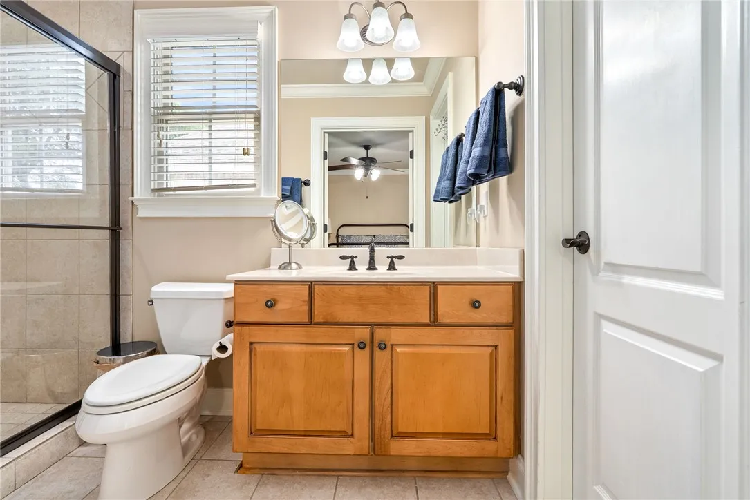 This bright bathroom features a vanity, window with blinds, and tiled shower area.