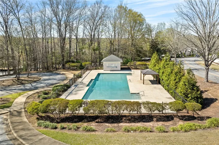 An inviting pool area with lush landscaping and a charming pool house awaits outdoor enjoyment.