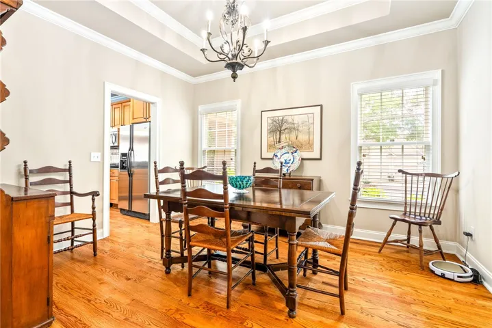 This bright dining area features polished hardwood floors and an elegant tray ceiling.
