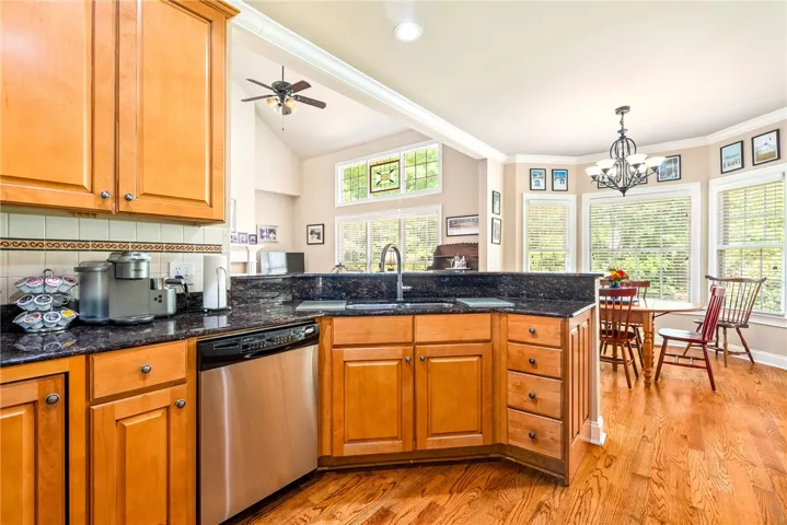This bright kitchen features wood flooring and a breakfast bar with granite counters, opening to a spacious living area.