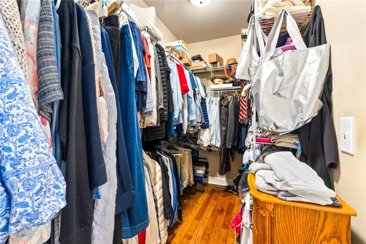 This organized walk-in closet offers extensive storage solutions with polished hardwood flooring.