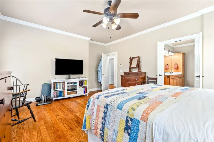 This spacious primary bedroom offers warm hardwood floors and convenient access to an en-suite bathroom.