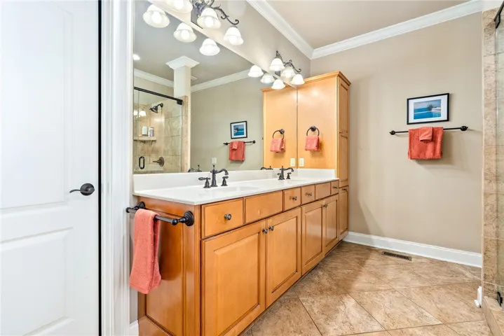 This bathroom features a double vanity and a spacious shower.
