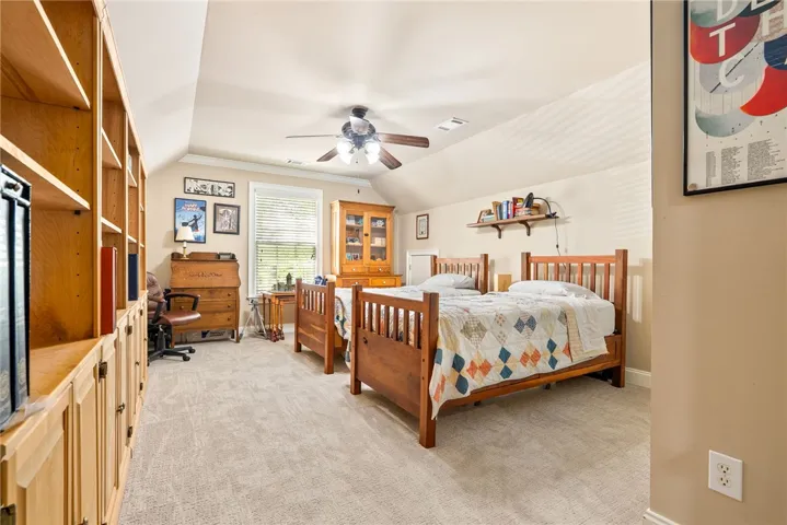This spacious bedroom offers ample built-in shelving, plush carpeting, and abundant natural light.