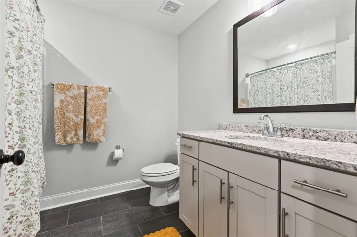 This clean and bright bathroom features elegant granite counters and durable tile flooring, perfect for daily routines.
