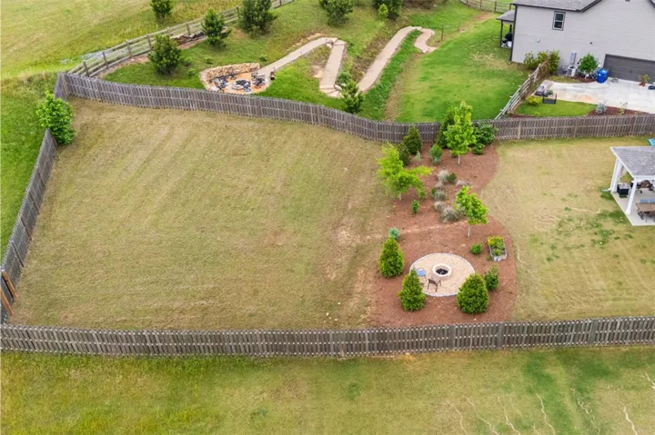 This spacious yard features a cozy fire pit area, a covered patio, and a well-maintained fence.