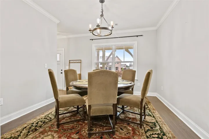 This inviting dining area features crown molding, hardwood flooring, and a classic chandelier.