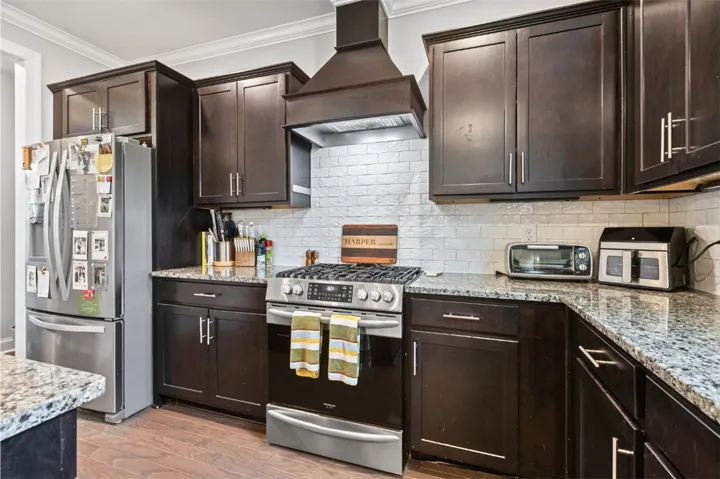This modern kitchen features dark cabinetry, light granite countertops, and hardwood flooring.