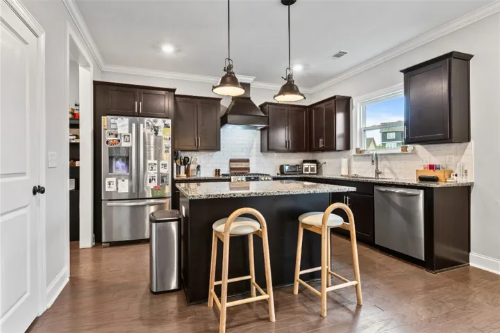 This functional kitchen features dark cabinetry, stainless steel appliances, and a central island.