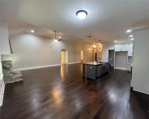 This expansive space features rich hardwood flooring, a stone fireplace, and an inviting kitchen island.