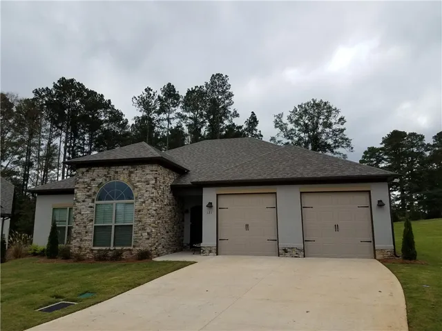 This charming home features a mix of natural stone and stucco, with a welcoming driveway.