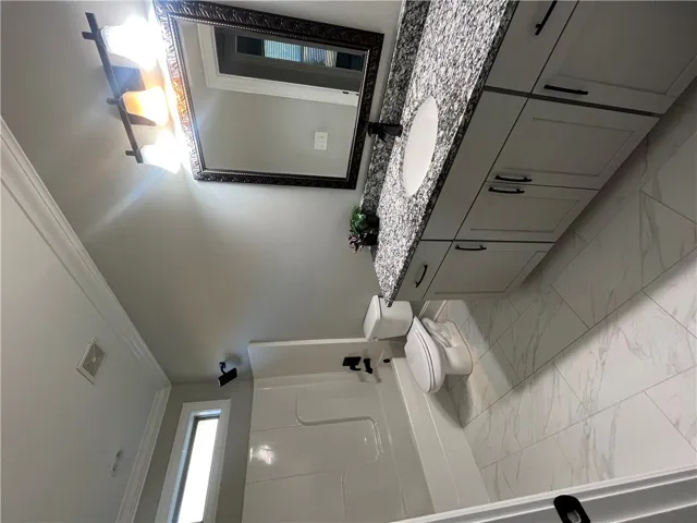 This bright bathroom features a spacious vanity and sleek flooring, perfect for daily routines.