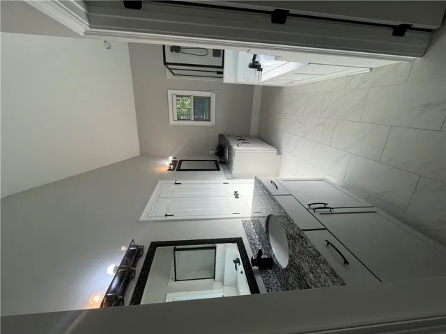 This bathroom features dual vanities and sleek tile flooring.