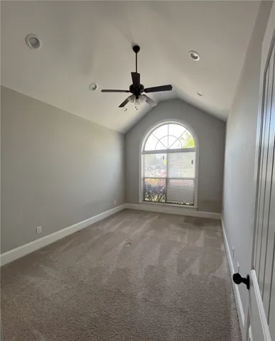 This airy room features a vaulted ceiling, arch-top window, recessed lighting, and soft carpet.