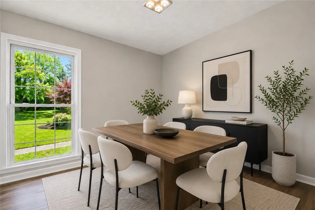 This bright dining area offers ample space for gatherings, complemented by elegant wood flooring and a refreshing view.