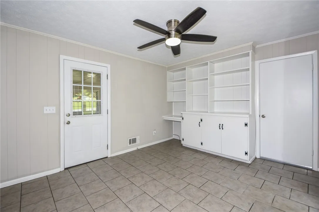 This versatile room features built-in shelving, a glass-paned door, and tiled floors for functional living.