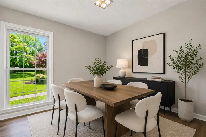 This bright dining area offers ample space for gatherings, complemented by elegant wood flooring and a refreshing view.