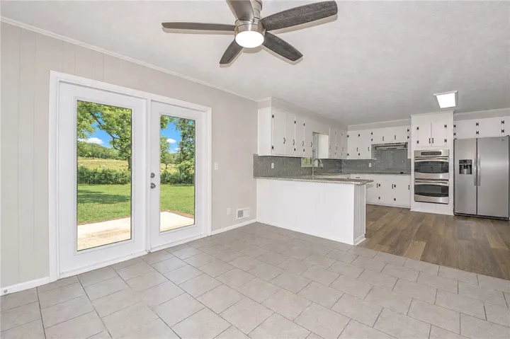 This spacious kitchen and dining area opens to a vibrant green outdoor space.