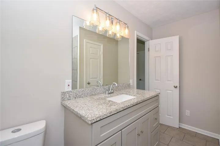 This bathroom features a sleek vanity with granite counters and a clean, tiled floor.