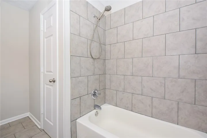 This bathroom features a sleek tiled shower and a classic white bathtub.