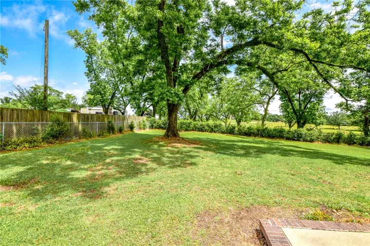 This spacious yard features mature trees and lush green grass, perfect for outdoor activities.