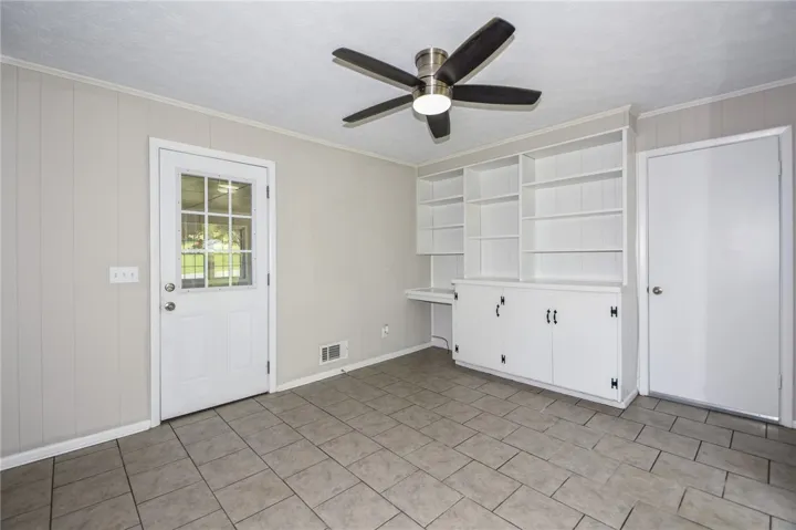 This versatile room features built-in shelving, a glass-paned door, and tiled floors for functional living.