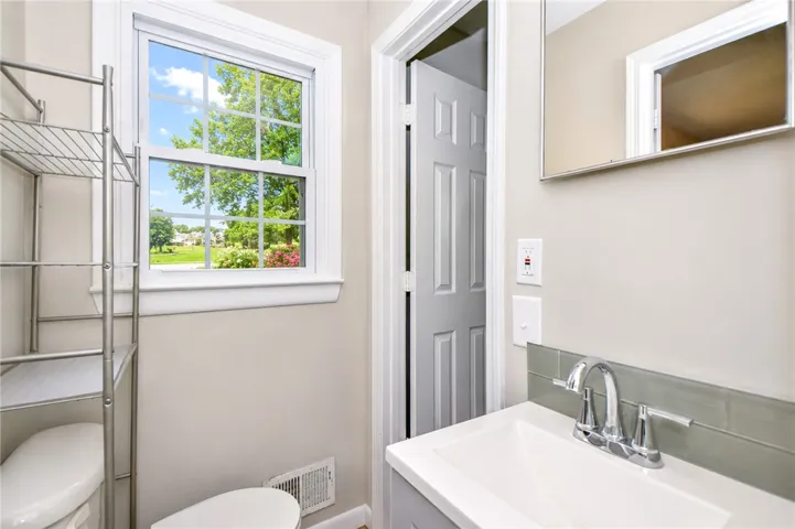 This bathroom features a contemporary vanity with a sleek faucet and a clear window offering natural light.