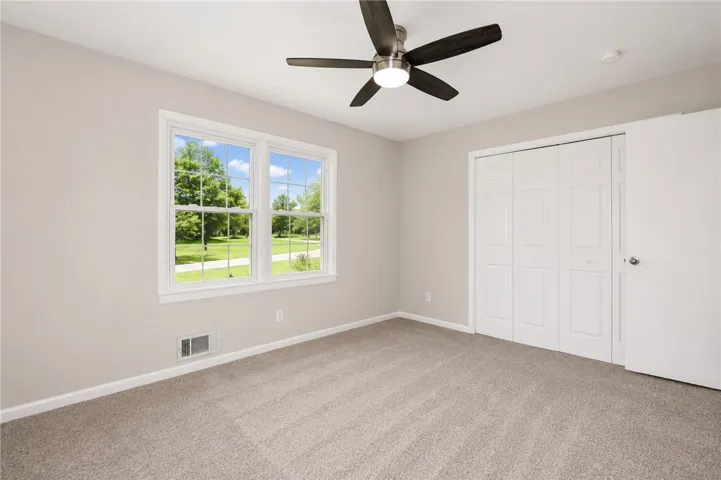 Bright and airy room with carpeted floors and a view of the surrounding greenery.