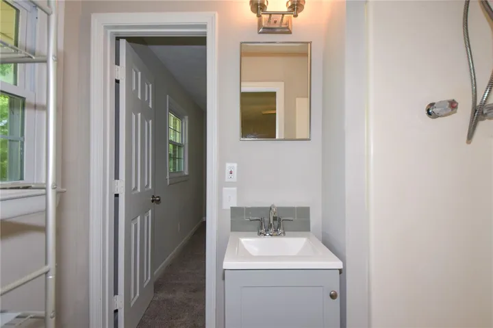 This functional bathroom features a sleek vanity and a well-lit mirror, offering practical elegance.