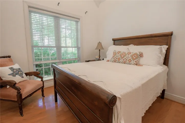 This inviting bedroom features rich hardwood flooring and abundant natural light.