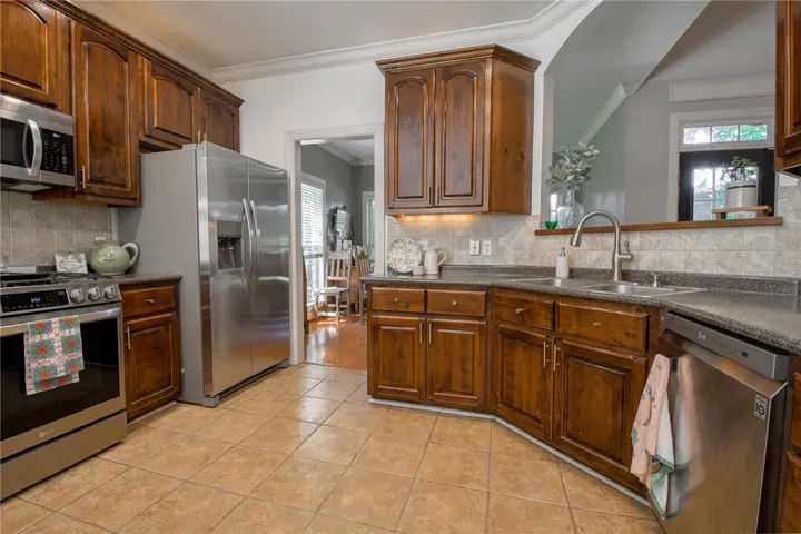 This kitchen features rich wood cabinetry, stainless steel appliances, and durable tile flooring.