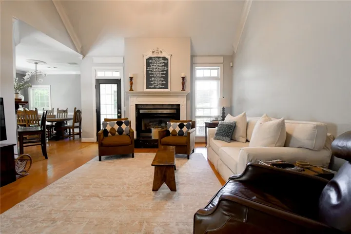 This inviting space features an elegant fireplace, an open floorplan, and rich hardwood flooring.