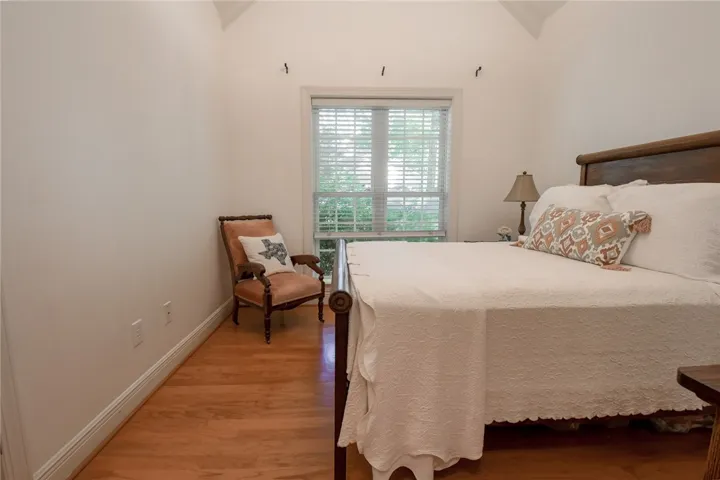 This serene bedroom offers a vaulted ceiling and hardwood floors, creating a spacious and inviting retreat.