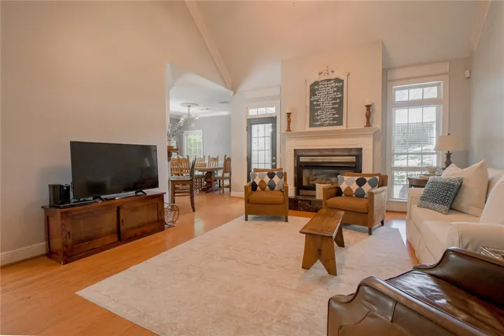 This inviting living space features an elegant fireplace, high ceilings, and rich hardwood flooring throughout.