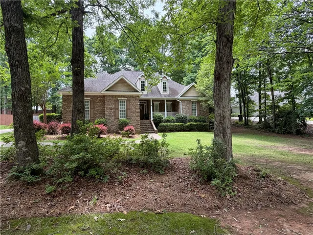 This charming home features a classic brick exterior, nestled amidst lush trees and vibrant landscaping.
