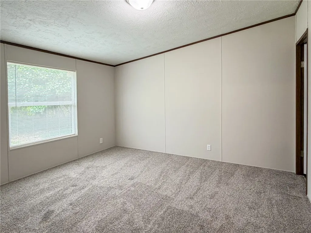 This spacious room features ample natural light and plush carpeting, offering a comfortable atmosphere.