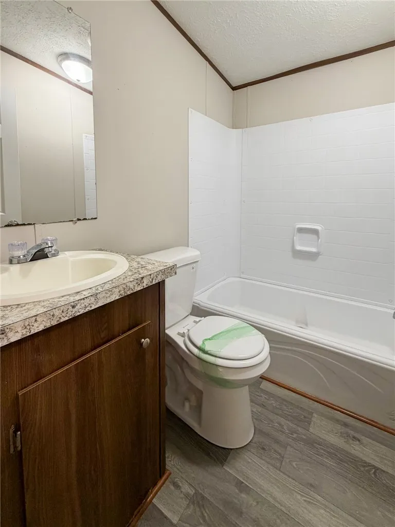 This functional bathroom features a clean tub, vanity, and toilet, offering practical comfort.