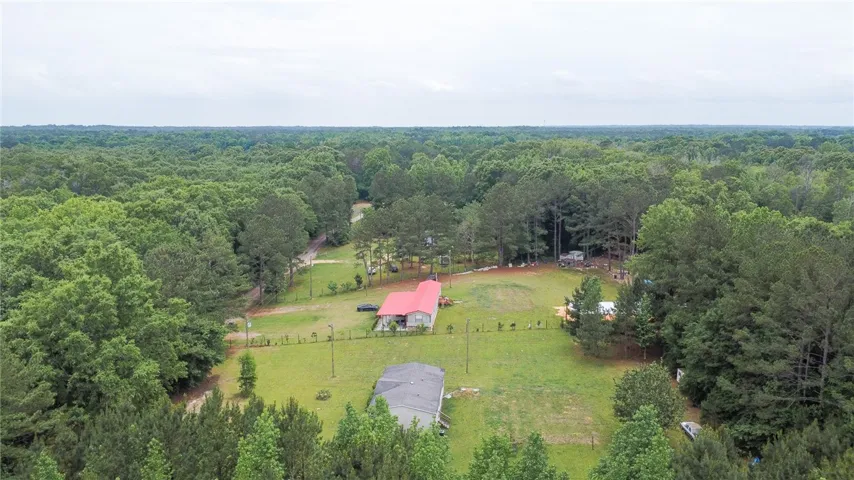 This expansive aerial view showcases a residential property nestled amidst abundant natural surroundings.