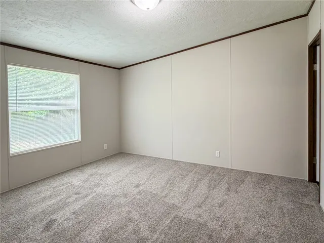 This spacious room features ample natural light and plush carpeting, offering a comfortable atmosphere.