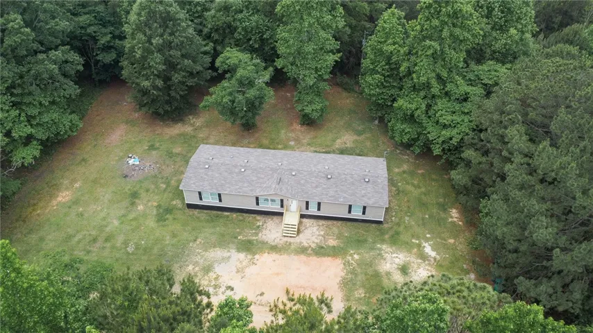 An aerial view showcases this property nestled in a lush, verdant landscape.