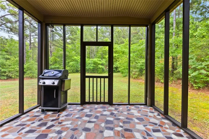 This screened-in porch offers tranquil views of the lush, verdant backyard.