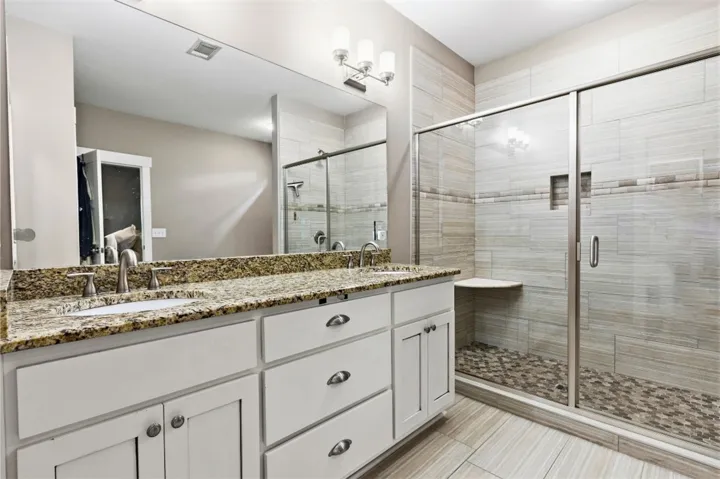 This serene bathroom offers a spacious walk-in shower and ample counter space.