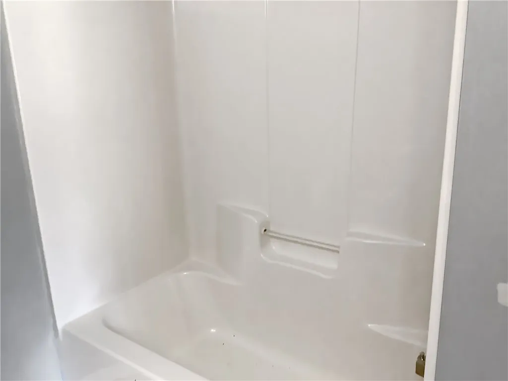 A pristine white tub and shower surround offers a clean, inviting space for daily refreshment.