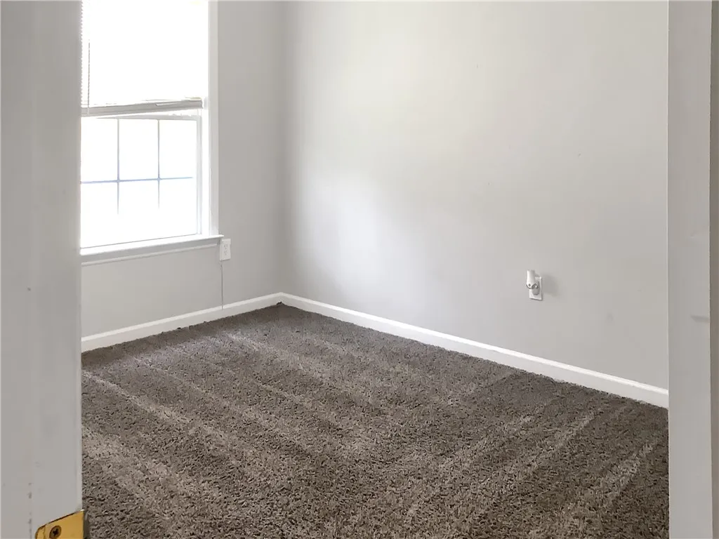 A well-lit bedroom features plush carpeting, creating a comfortable and inviting atmosphere.