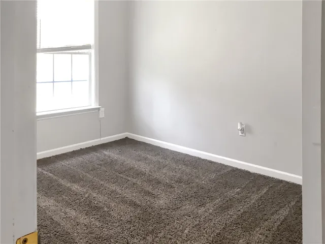 A well-lit bedroom features plush carpeting, creating a comfortable and inviting atmosphere.